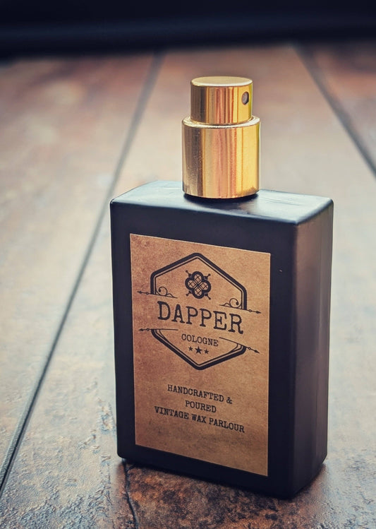 Perfume bottle with gold cap and 'Dapper' label on a wooden surface