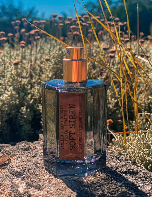 Perfume bottle labeled 'Soft Siren' on a stone surface with a natural background