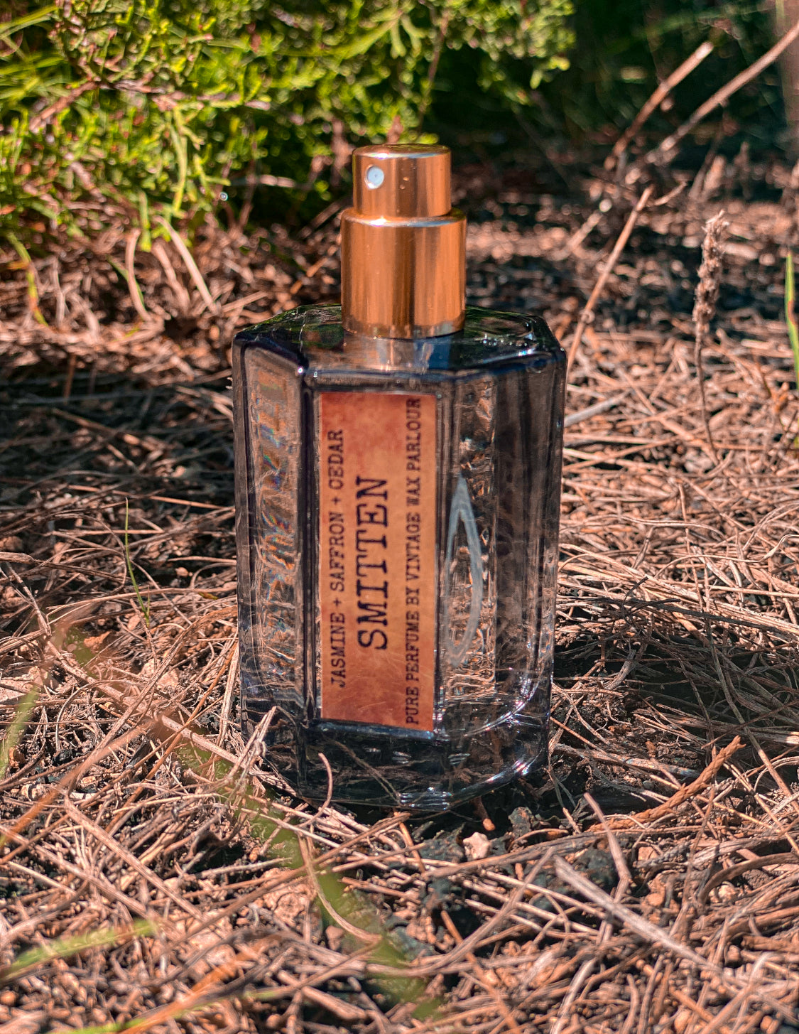 Perfume bottle labeled 'Smitted' on a natural background