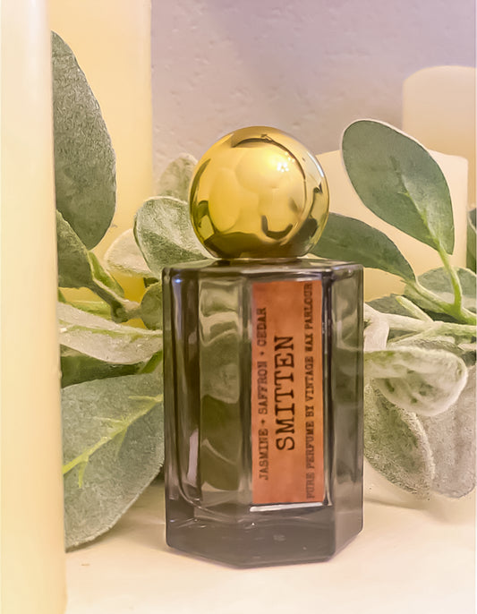 Perfume bottle with gold cap on a light background with green leaves