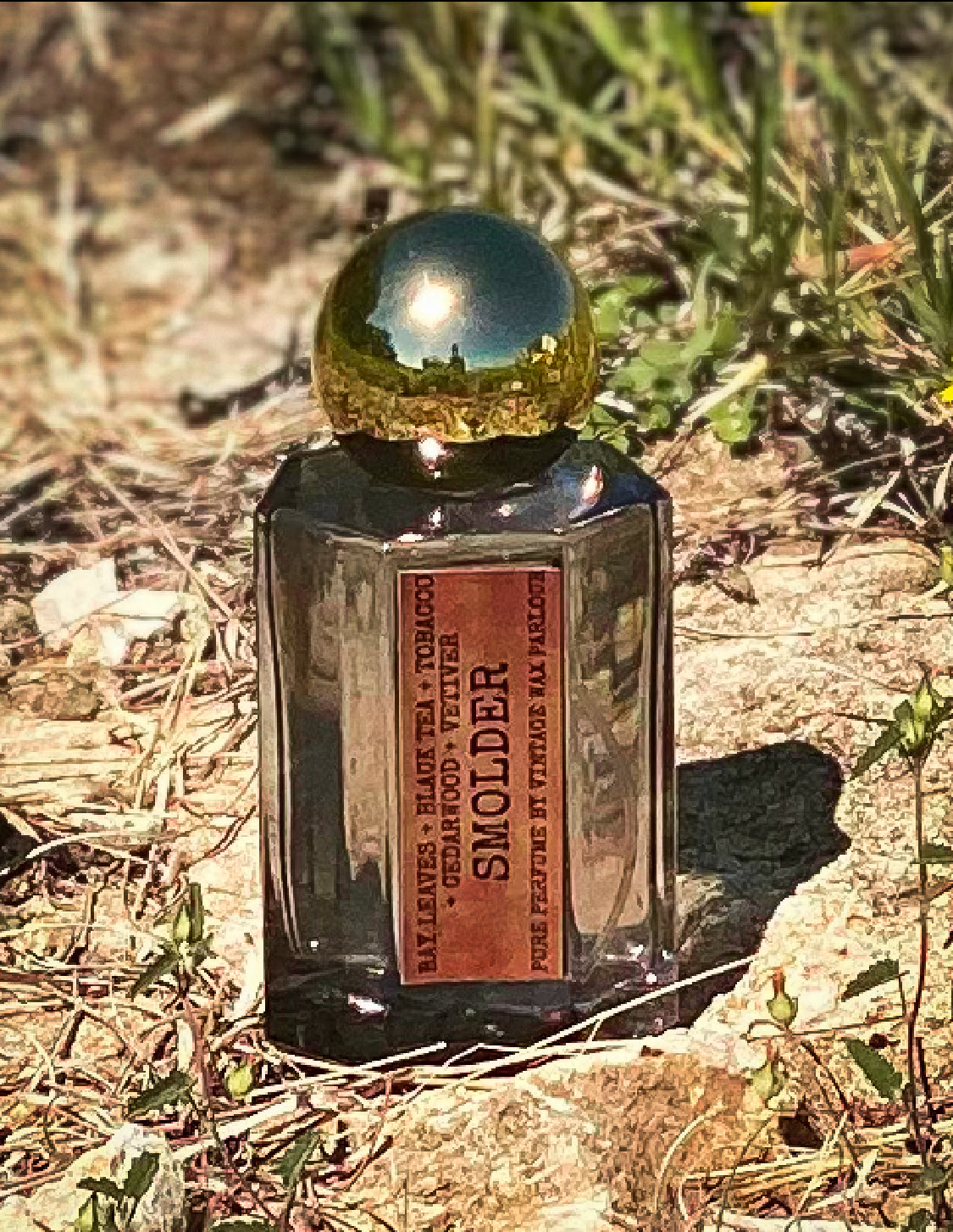 Perfume bottle labeled 'Smolder' on a natural background