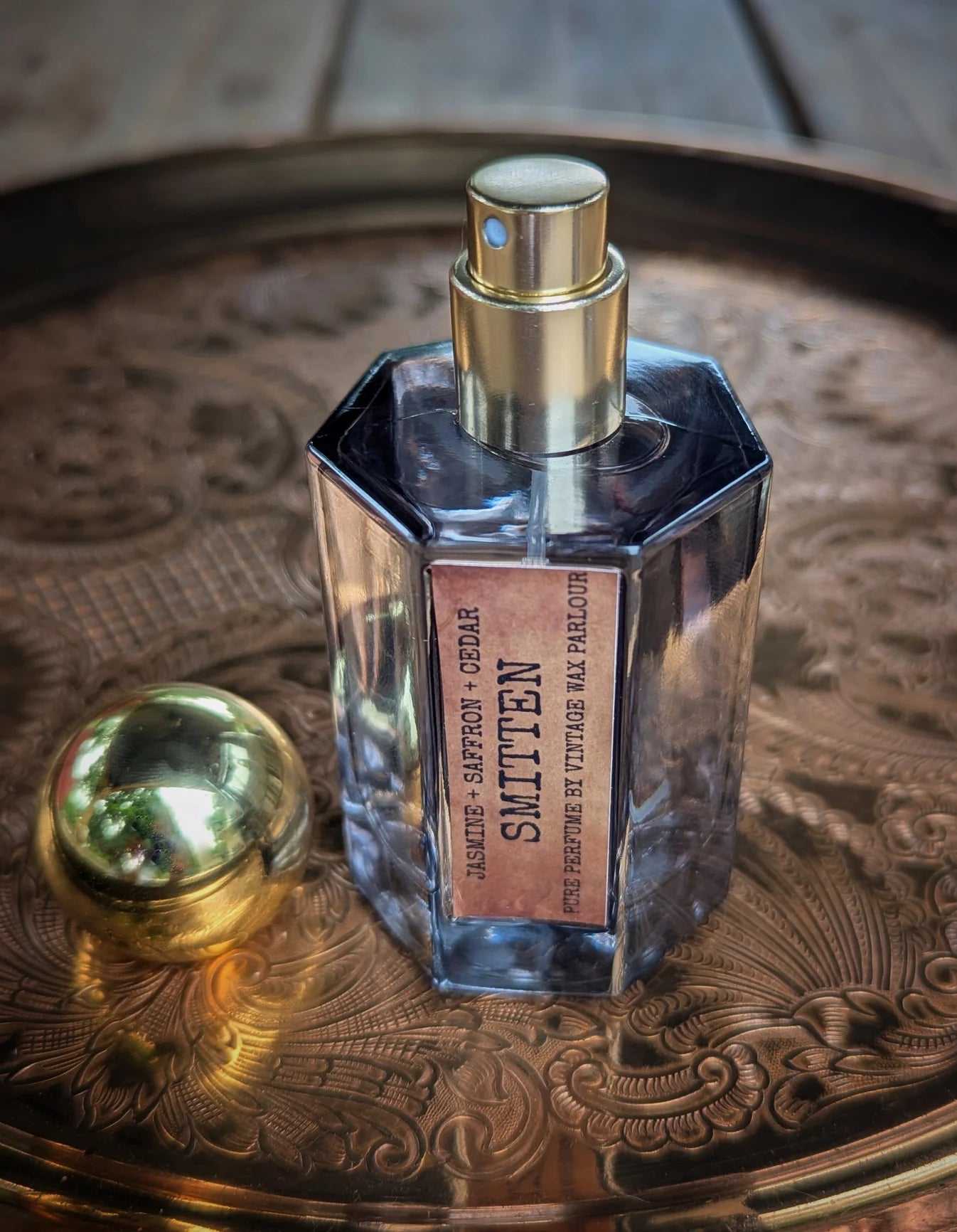 Perfume bottle with gold cap on a decorative metal tray