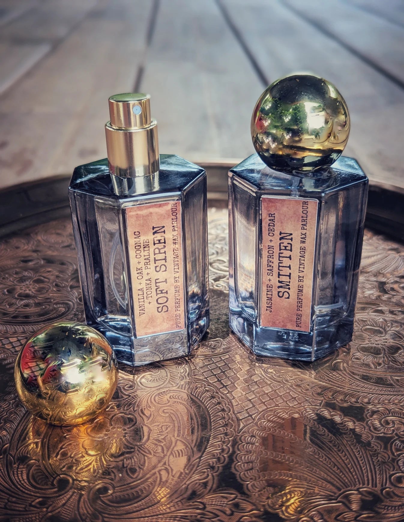 Two perfume bottles with gold caps on a decorative surface