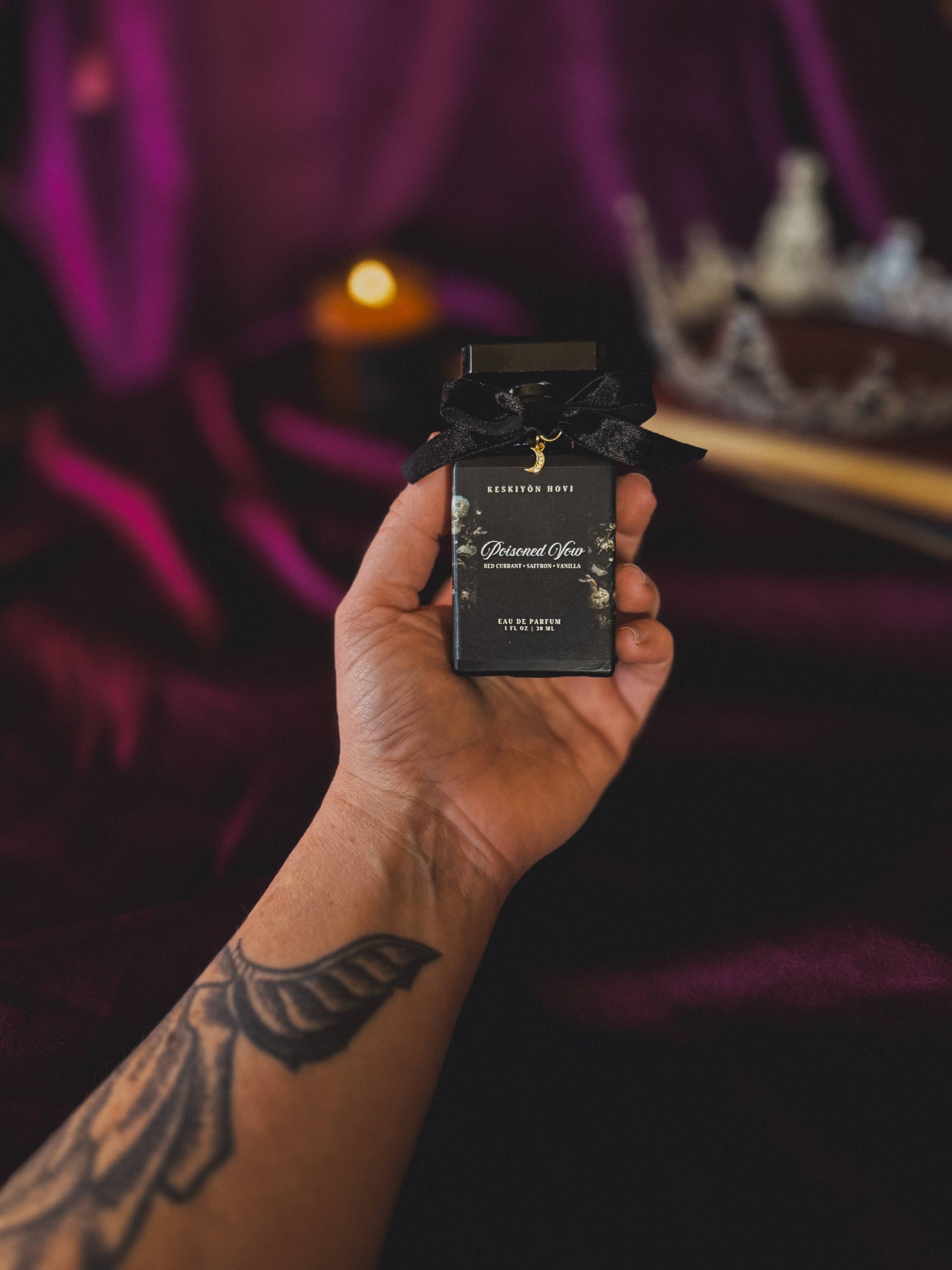 Hand holding a black perfume bottle with a blurred background