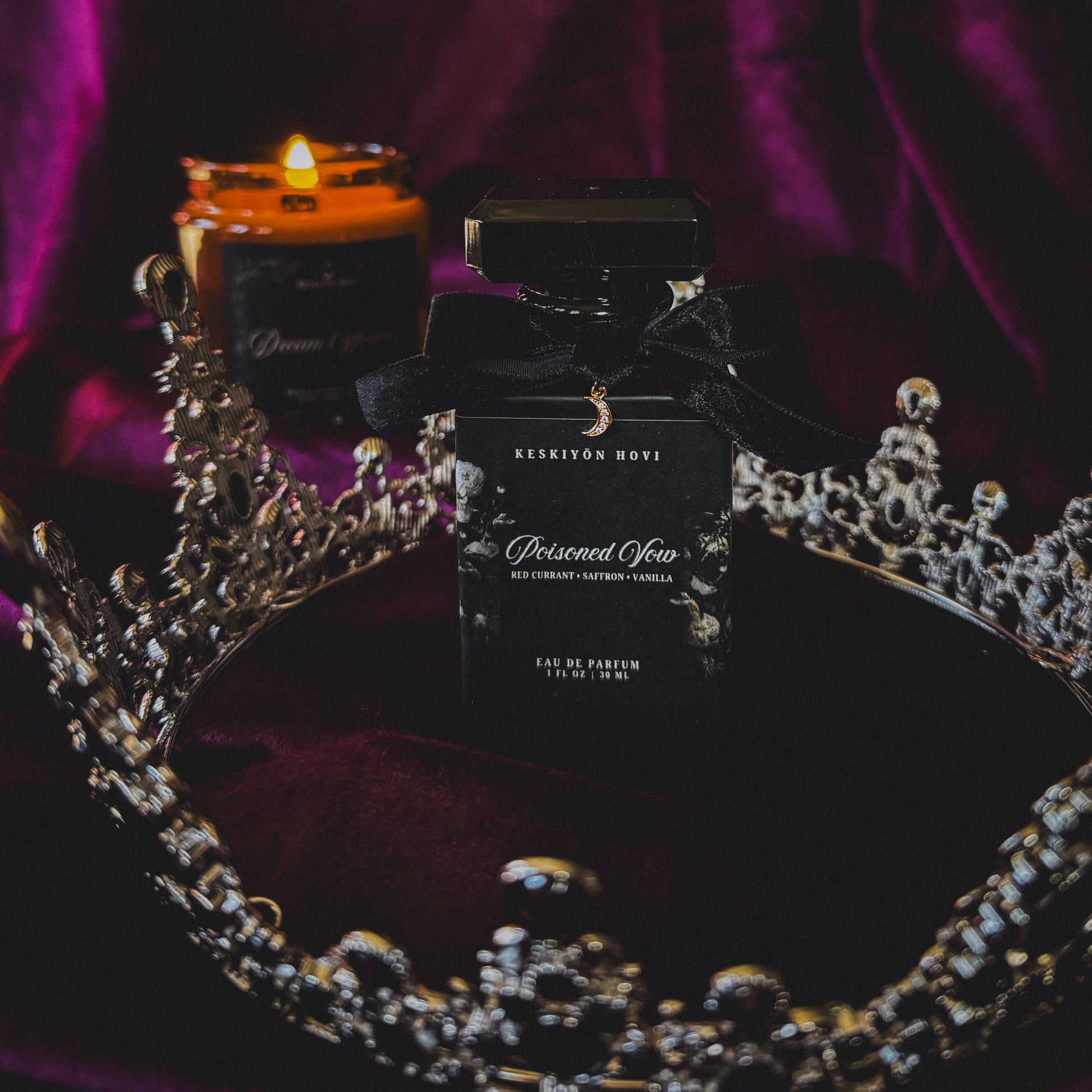 Perfume bottle labeled 'Poisoned vow' on a decorative surface with a candle and crown.