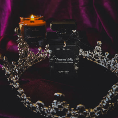 Perfume bottle labeled 'Poisoned vow' on a decorative surface with a candle and crown.
